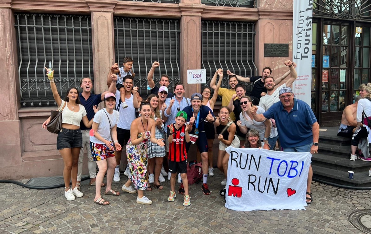 Friends and family cheering with a “Run Tobi Run” banner